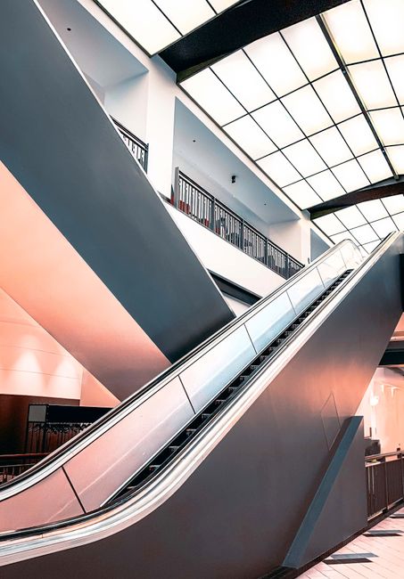 A large, intricate glass-domed ceiling with a prominent circular clock at its center, situated inside Liberty Shopping Centre. The interior features multiple levels with balconies and shops, illuminat